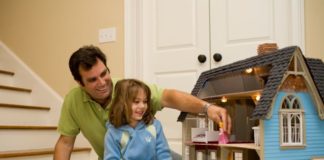 Dad and daughter play with doll house
