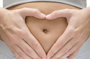 Woman making heart shape on belly