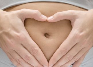 Woman making heart shape on belly