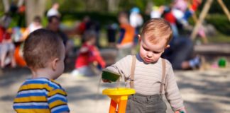 Two little boys play outdoors in a sand pit.