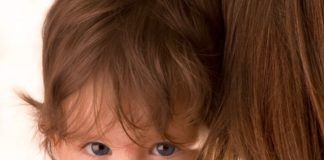 A child peers over his mother's shoulder.