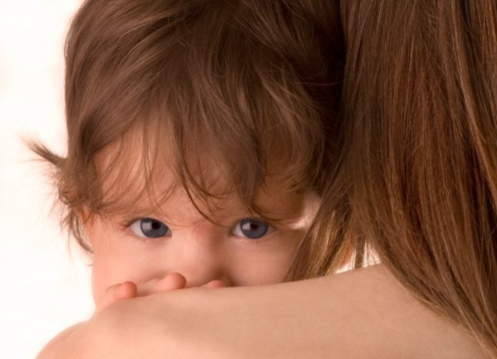 A child peers over his mother's shoulder.