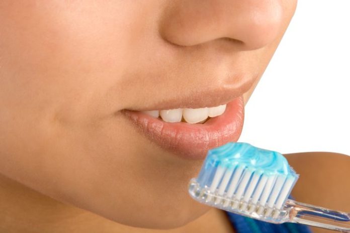 A close up of a face and toothbrush.