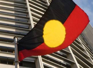 A flag that is black on top and red on the bottom with a large yellow circle in the middle.