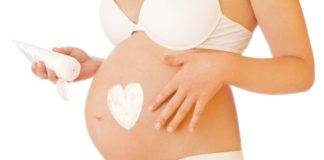 Pregnant woman putting on cream