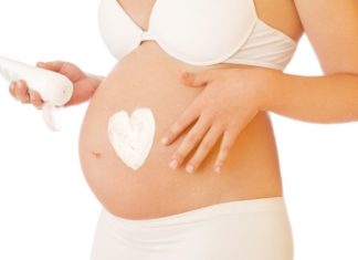 Pregnant woman putting on cream