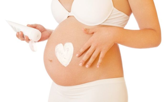 Pregnant woman putting on cream