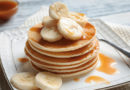 Plate with yummy banana pancakes on kitchen table