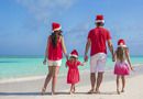 Back view young family of four in Santa Hat on tropical beach