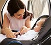 Mother Putting Baby Son Into Car Travel Seat