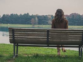 Young woman sitting on a bench in a city park