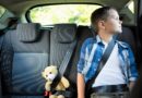 Teenage boy sitting with teddy bear in the car