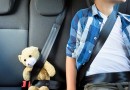 Teenage boy sitting with teddy bear in the car
