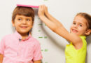 Boy and girl measure height by wall scale at home