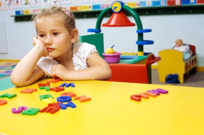 An unhappy girl in a classroom setting.