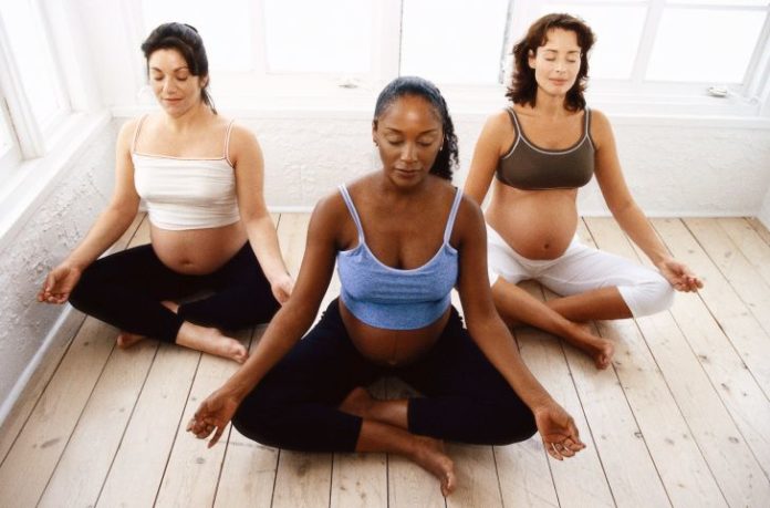 Three pregnant women meditating.