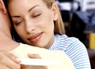 A couple hugging holding a pregnancy test