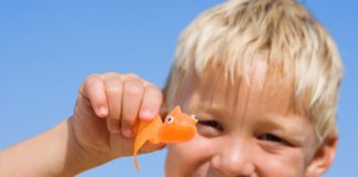 Blond boy in the sun with toy orange fish.