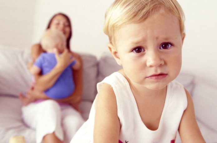 Unhappy toddler with mother and sibling.