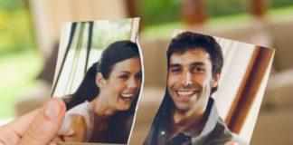 A woman's hands hold a torn photo of a couple