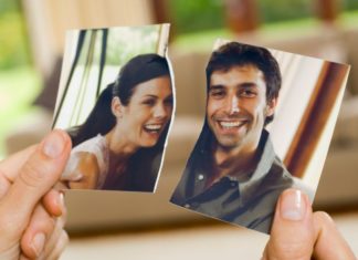 A woman's hands hold a torn photo of a couple