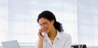 A woman with a telephone and laptop computer.