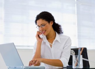 A woman with a telephone and laptop computer.