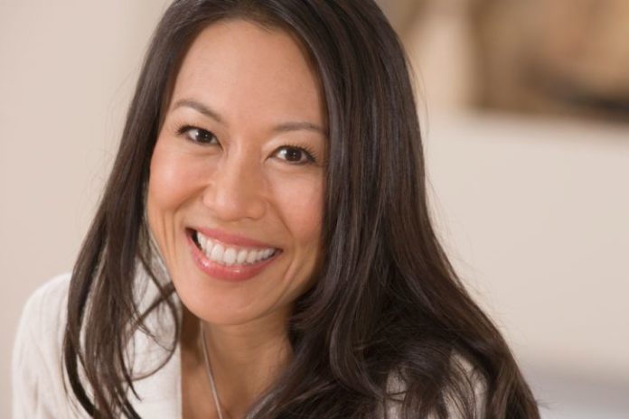 A happy portrait of a young woman with long dark hair.