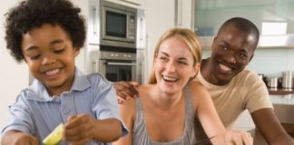 A happy couple with a cute toddler are making a salad.