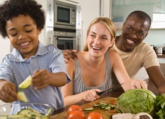 A happy couple with a cute toddler are making a salad.
