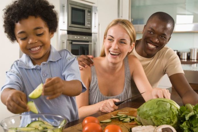 A happy couple with a cute toddler are making a salad.
