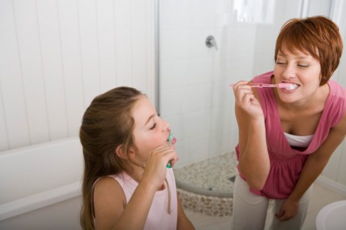 Mother and daughter brushing teeth