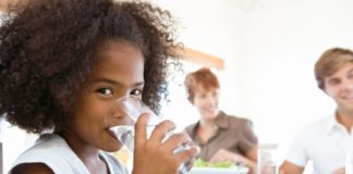 Girl drinking water at dinner.