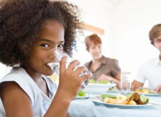 Girl drinking water at dinner.