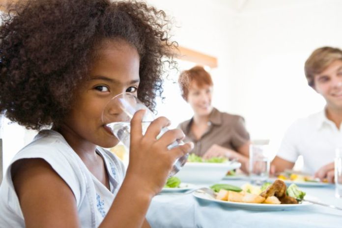 Girl drinking water at dinner.