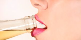 Close up of a woman drinking alcohol from a bottle.