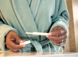Woman in bathrobe holds a pregnancy test.