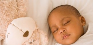 Sleeping baby next to a stuffed animal.