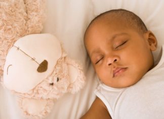 Sleeping baby next to a stuffed animal.