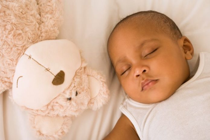 Sleeping baby next to a stuffed animal.