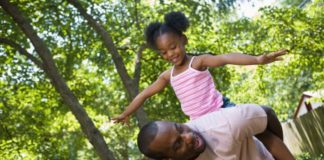 Father and daughter playing outside. The girl is on her father's back.