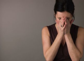 Woman covering face with hands.