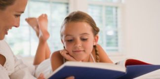 Girl reading book with mother