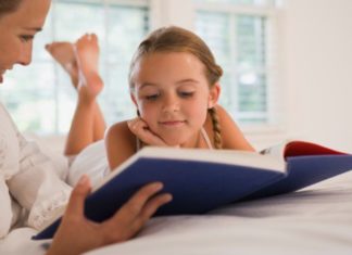 Girl reading book with mother