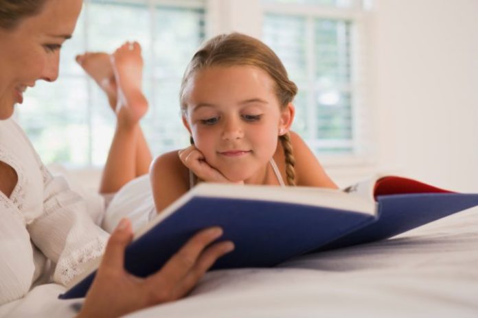 Girl reading book with mother