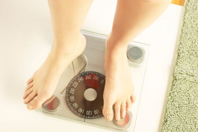 A view of a person's feet as they stand on a scale.