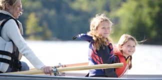 Mother and two daughters in rowboat on the water.