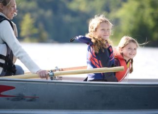 Mother and two daughters in rowboat on the water.