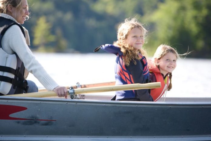 Mother and two daughters in rowboat on the water.