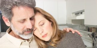 A man holds a woman. She looks unwell.